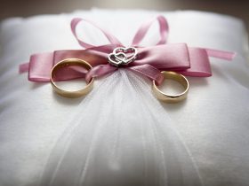 selective focus photography of silver colored engagement ring set with pink bow accent on throw pillow