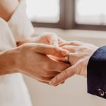 woman putting ring on person s hand