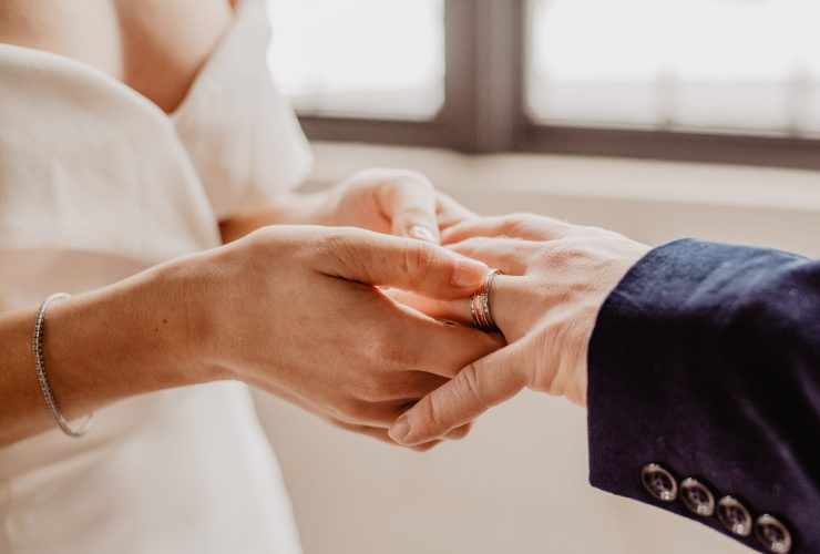 woman putting ring on person s hand