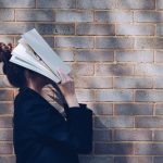 woman covering her face with white book