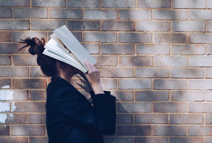 woman covering her face with white book