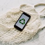 mobile phone with green recycling sign and mesh bag