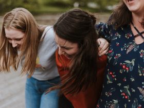 three woman holding each other and smiling while taking a photo