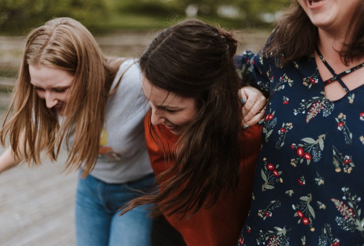 three woman holding each other and smiling while taking a photo