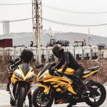 man in black helmet riding yellow sports bike during daytime