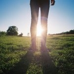 person in black pants standing on green grass field during daytime