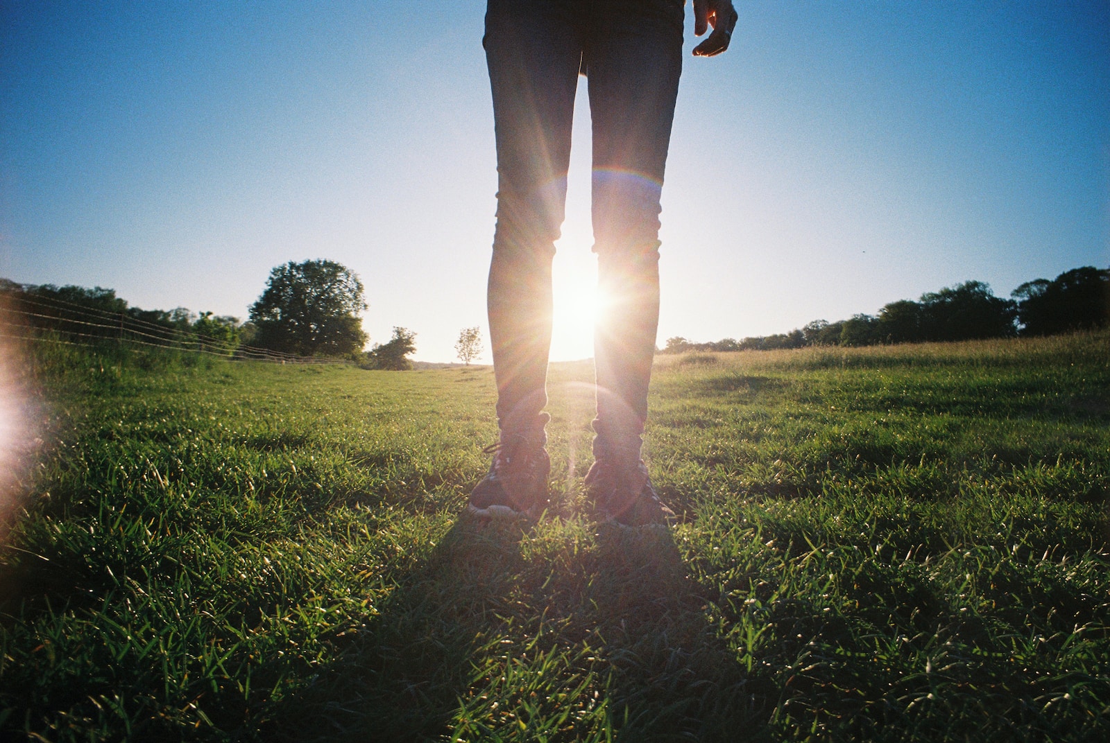 person in black pants standing on green grass field during daytime