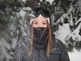 woman with mask standing beside pine tree covered with snow