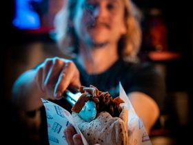 a woman holding a sandwich in front of a bar