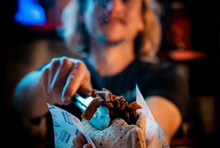 a woman holding a sandwich in front of a bar