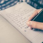 person writing bucket list on book