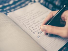 person writing bucket list on book