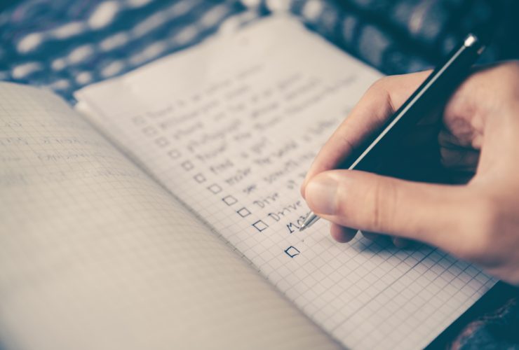 person writing bucket list on book