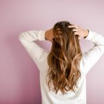 woman in white long-sleeved shirt standing in front of pink wall