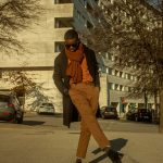 a man in brown pants and an orange scarf