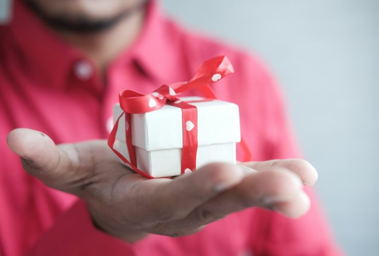 a man holding a white gift box with a red ribbon