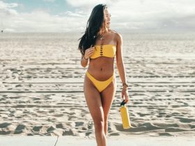 standing woman wearing yellow bikini holding yellow bottle