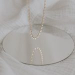 gold necklace on white textile