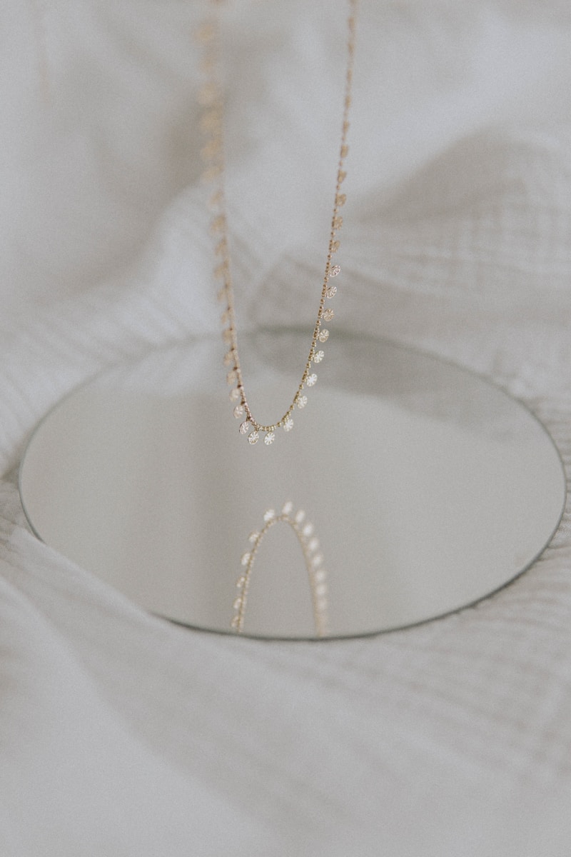 gold necklace on white textile