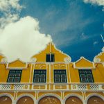 a yellow building with a clock on the front of it