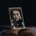 an open book sitting on top of a bed next to a laptop computer