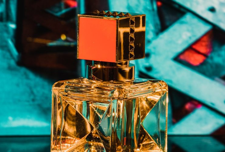 clear glass perfume bottle on blue surface