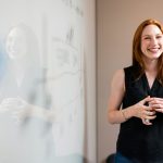 woman in blue tank top standing beside white wall