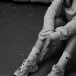 a black and white photo of a girl sitting on the floor