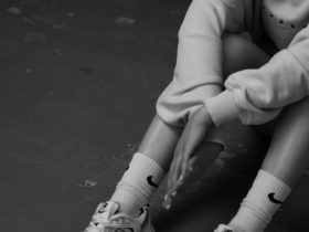 a black and white photo of a girl sitting on the floor