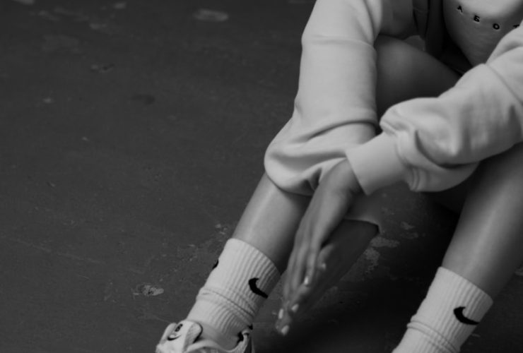 a black and white photo of a girl sitting on the floor