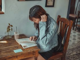 Vrouw die rustig schrijft in een notitieboekje in een gezellig café, als symbool voor bewuste zelfreflectie