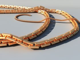 Gouden zomerse sieraden zoals schakelkettingen en enkelbandjes op een strandhanddoek