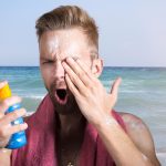 Minerale zonnebrand op het strand naast zonnebril en handdoek