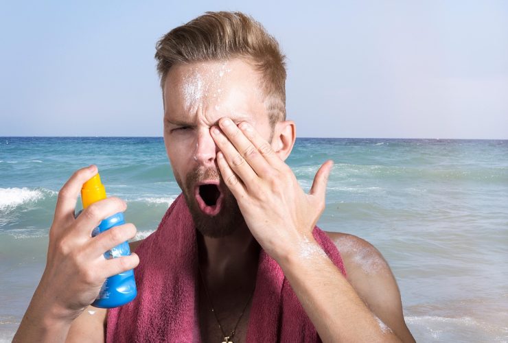 Minerale zonnebrand op het strand naast zonnebril en handdoek