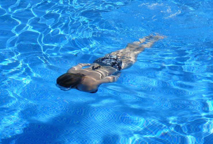 Man in zwembroek bij buitenzwembad in de zomer