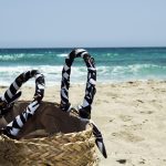 Geweven strandtas liggend op zand bij de zee