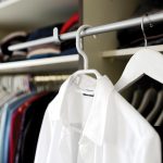 Een overzichtelijke zomercapsulegarderobe met neutrale kledingstukken netjes op een rek gehangen