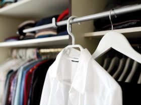 Een overzichtelijke zomercapsulegarderobe met neutrale kledingstukken netjes op een rek gehangen