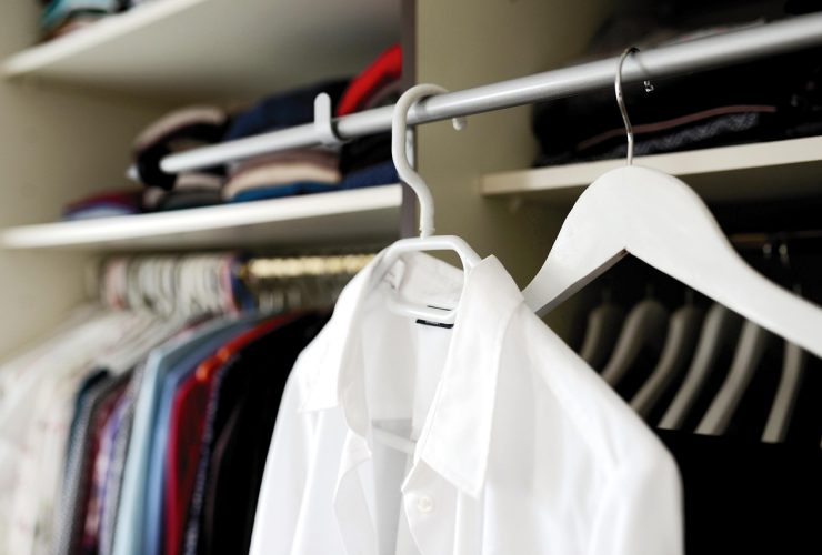 Een overzichtelijke zomercapsulegarderobe met neutrale kledingstukken netjes op een rek gehangen