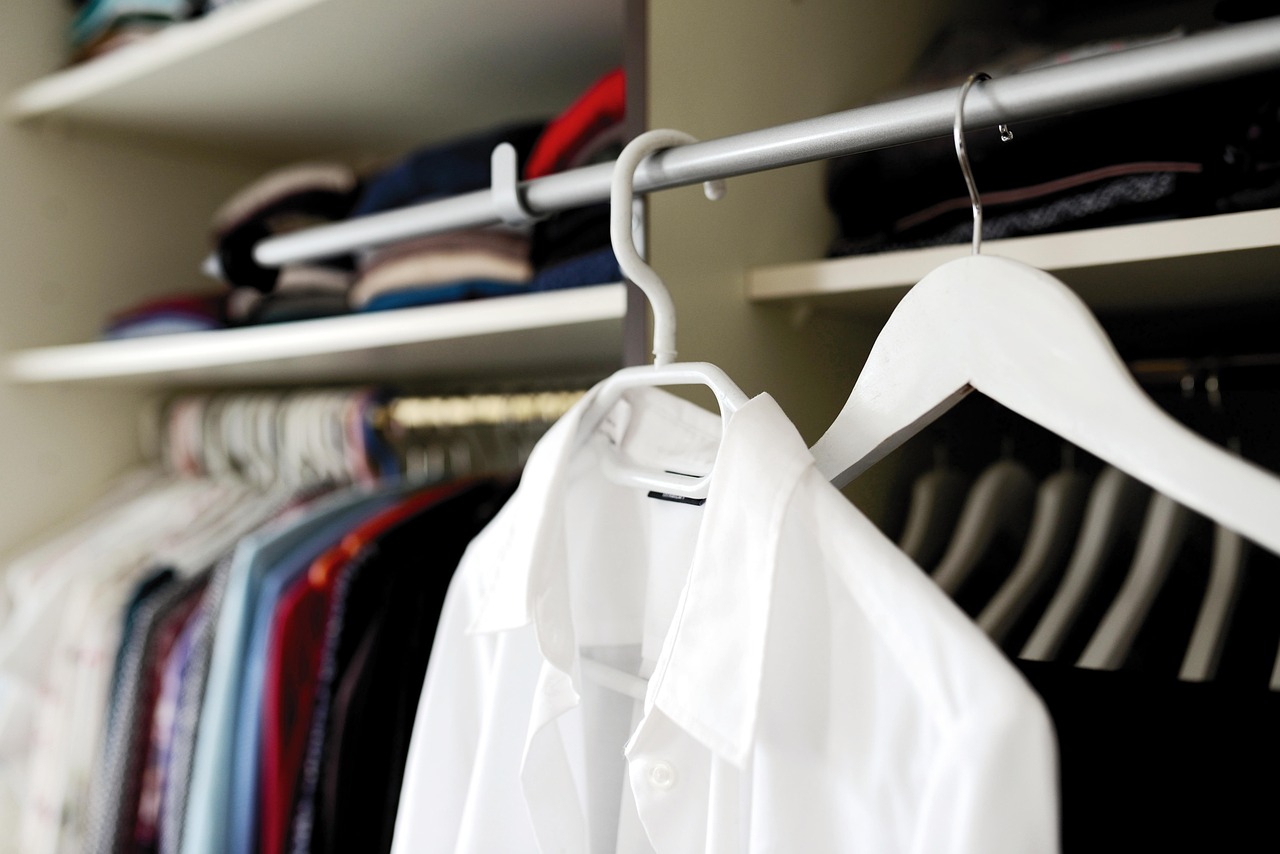 Een overzichtelijke zomercapsulegarderobe met neutrale kledingstukken netjes op een rek gehangen