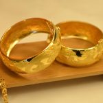 Een gouden erfstuk ring naast een modern sieradeontwerp op een witte achtergrond