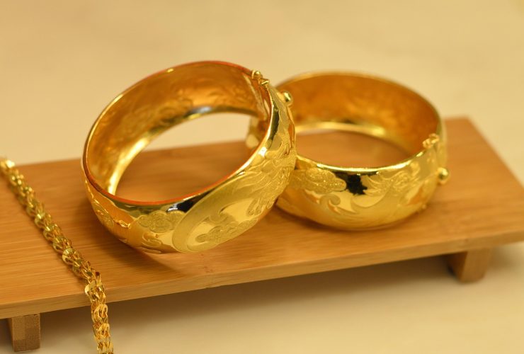 Een gouden erfstuk ring naast een modern sieradeontwerp op een witte achtergrond