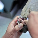 Collega's maken samen sieraden aan een tafel vol kralen en draad tijdens een teambuilding workshop