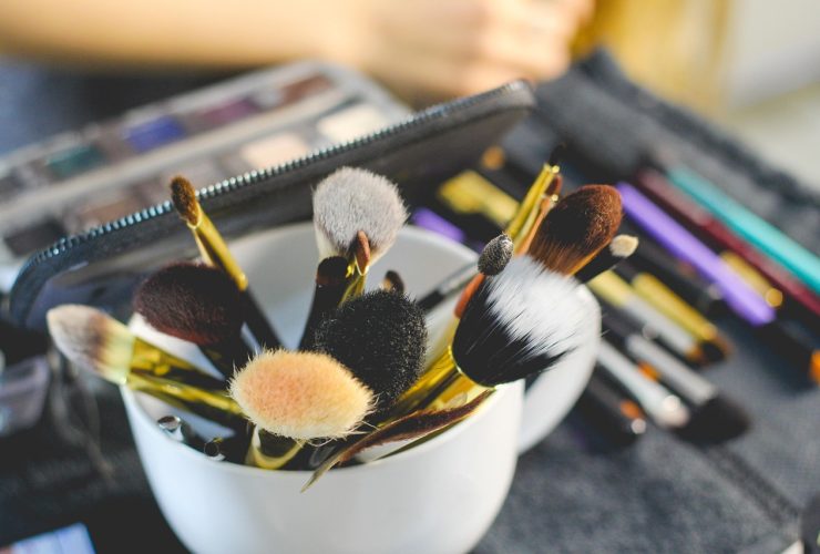 Verschillende make-upproducten uitgestald op een witte ondergrond, waaronder mascara, foundation en lippenstift