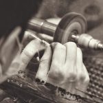 Ambachtelijke zilversmid aan het werk met gereedschap en sieraden in een kleine werkplaats