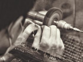 Ambachtelijke zilversmid aan het werk met gereedschap en sieraden in een kleine werkplaats