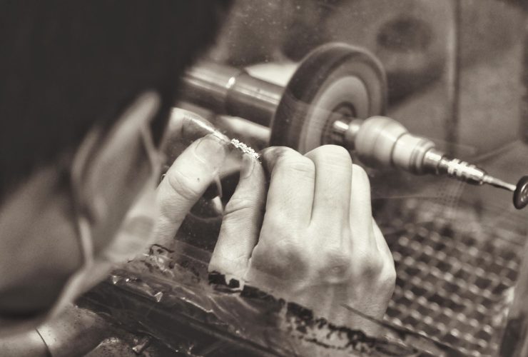 Ambachtelijke zilversmid aan het werk met gereedschap en sieraden in een kleine werkplaats